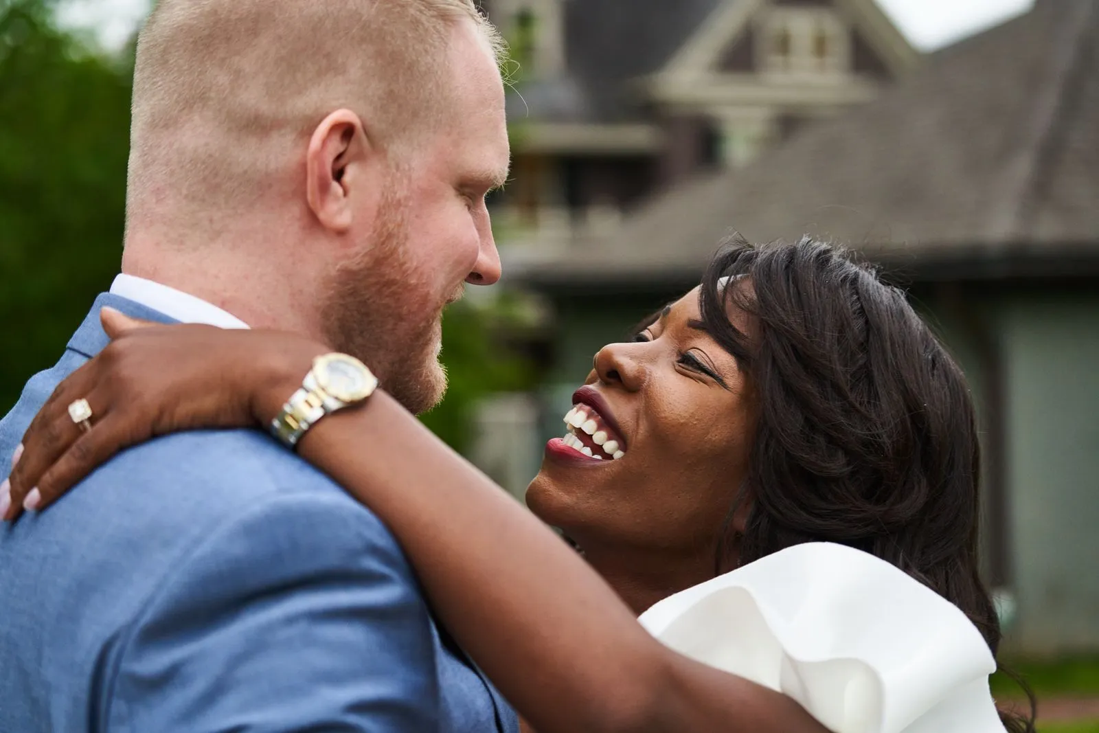 Happy couple embracing in a loving moment on their wedding day outside with a classic backdrop.